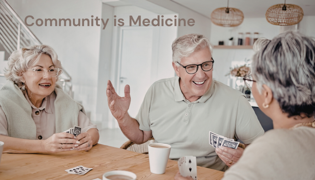 Three people sat together around a table playing a game of cards with a cup of tea, they are laughing.